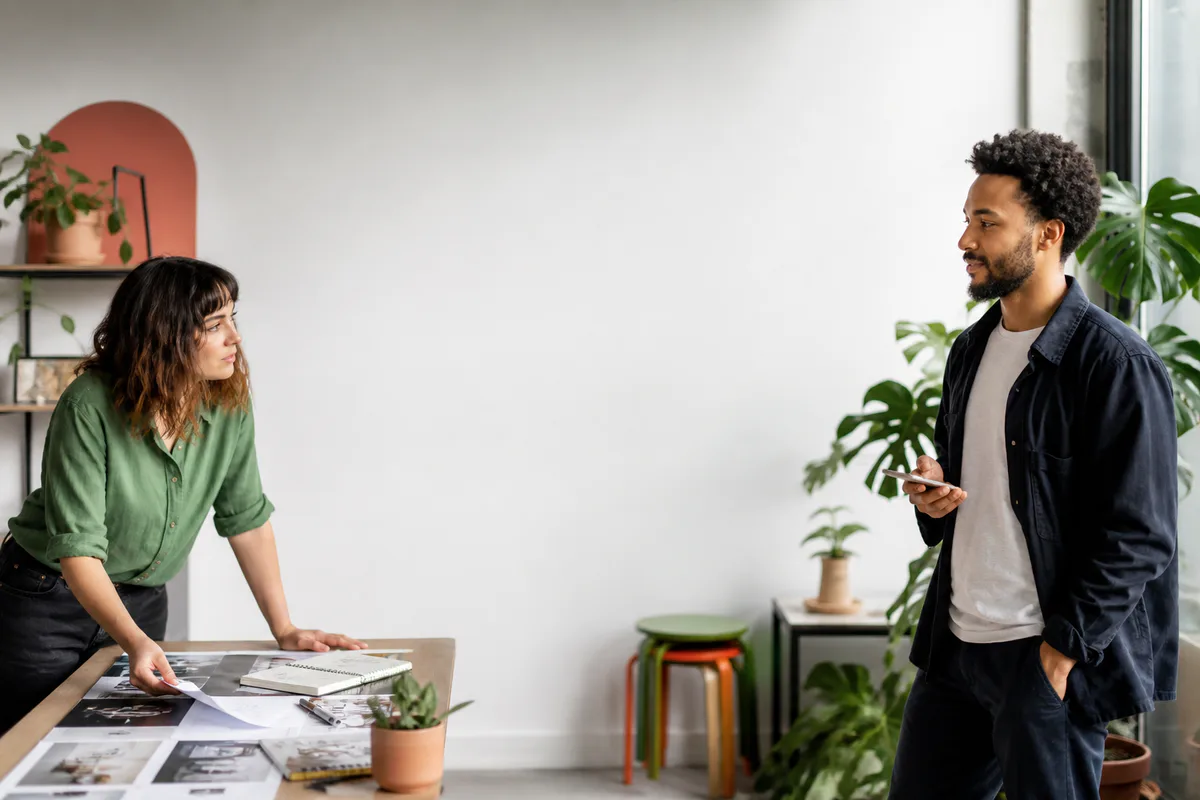 Two creative coworkers planning an event across a shared studio
